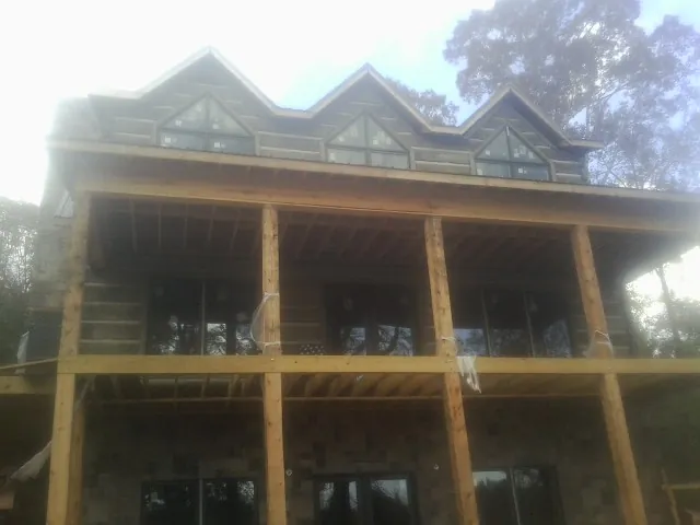 Dormers and porch framing on a large log home under construction — Roof Coating work by our crew in Marietta